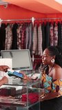 Vertical Video, Contactless payment in Africa. A customer makes a successful transaction via mobile point of sale, POS terminal at a fashion clothing boutique store - Powered by Shutterstock - Get 15% off with code: PIKWIZARD15