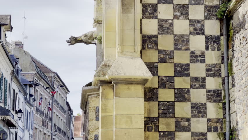 Gothic gargoyles and flint-limestone checkerboard wall of Saint-Martin Church, Saint-Valery-sur-Somme, Picardy, with ornate tracery, lancet windows and slate roof details under a bright autumn sky