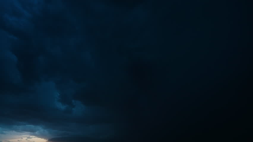 Lightning flashes illuminate textured storm clouds as they roll across the night horizon. A moody timelapse showcasing thunder, atmosphere, and the immense power of nature in motion
