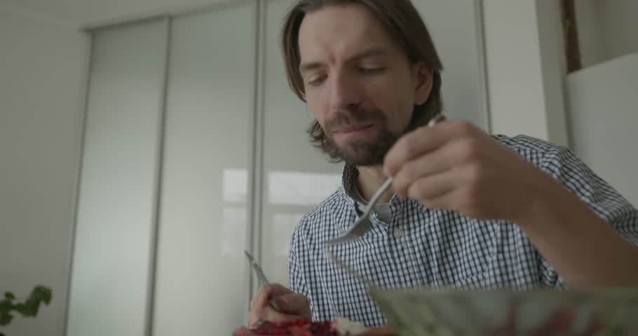 Man is Eating Breakfast in Kitchen. 4K 10-bit