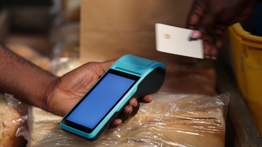 Contactless payment in Africa. Customer makes successful transaction using point of sale, POS terminal at a local bakery - Powered by Shutterstock - Get 15% off with code: PIKWIZARD15