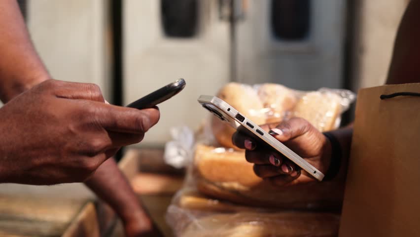 Customer makes mobile money payment at bread bakery using smartphone, showcasing fintech, contactless and cashless transactions in Africa - Powered by Shutterstock - Get 15% off with code: PIKWIZARD15