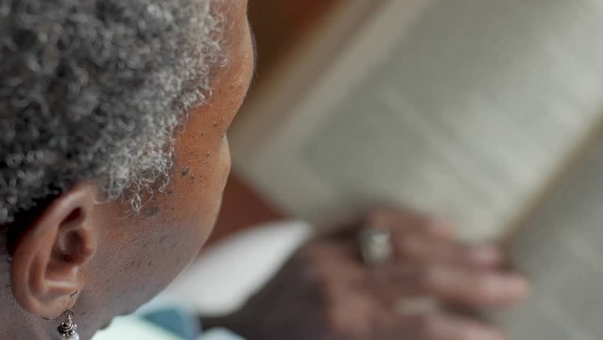 Elderly individual deeply engaged in reading a book indoors, emphasizing learning and intellectual growth. Soft lighting enhances peaceful and focused environment.