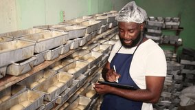 African baker entrepreneur using a tablet to manage inventory of fresh bread dough in his busy bakery, successful small business owner SME - Powered by Shutterstock - Get 15% off with code: PIKWIZARD15