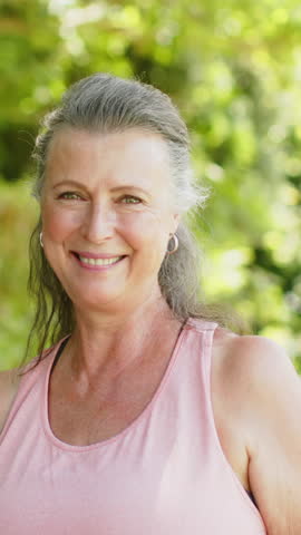 Vertical video: Reacting to off-camera cue Senior woman with silver hoops laughing in garden. Joy, leisure, outdoor, natural, candid, happiness, vertical video