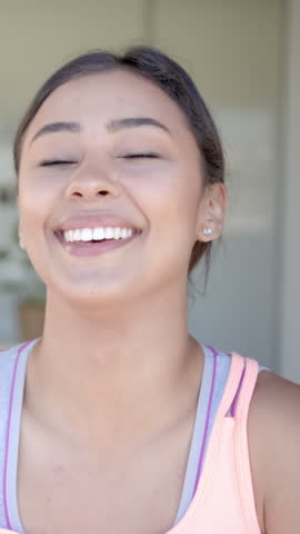 Vertical video: After hearing funny joke, woman laughing loudly, easing into smile on porch. Joy, happiness, positivity, candid, natural, relaxed, vertical video