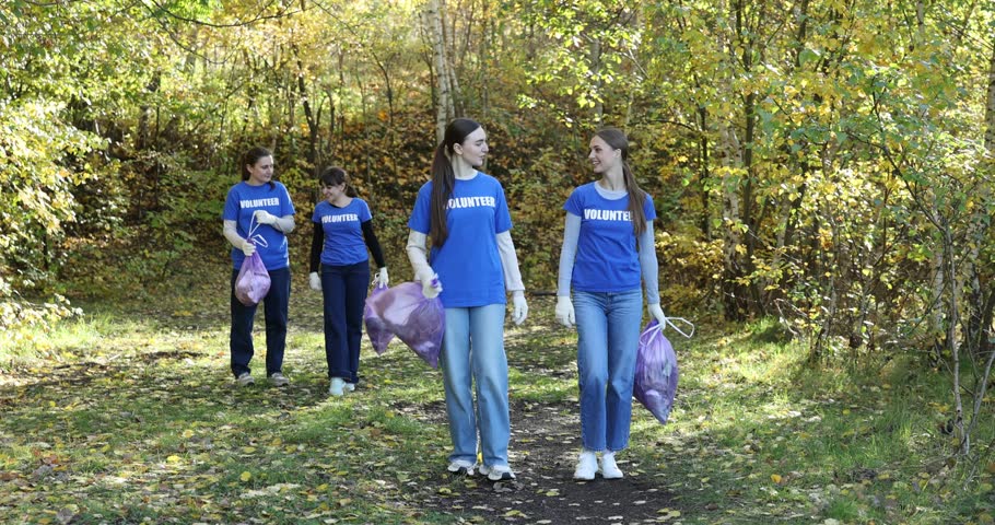 Group of happy volunteers with bags of trash in park