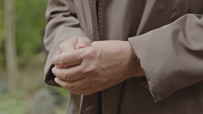 A poignant close-up of a grieving widow’s hands captures raw emotion during a quiet cemetery visit.
