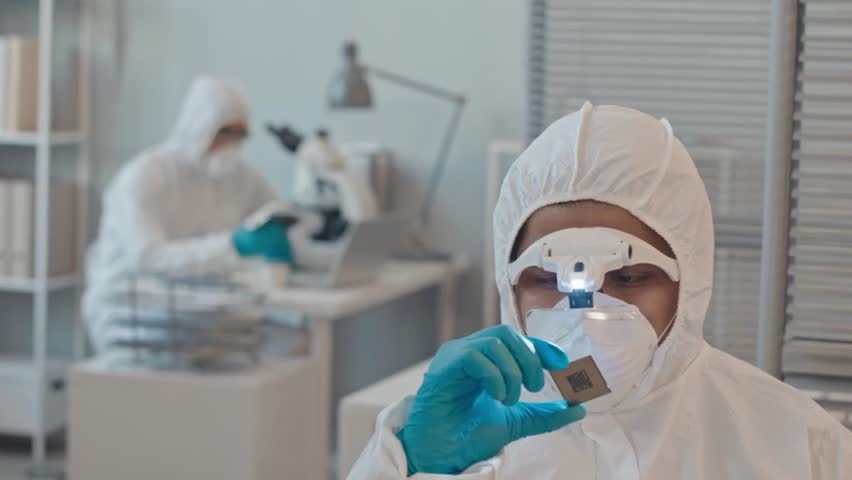 A skilled engineer in protective gear inspects a computer chip under lab lighting, focusing on precision.
 - Powered by Shutterstock - Get 15% off with code: PIKWIZARD15