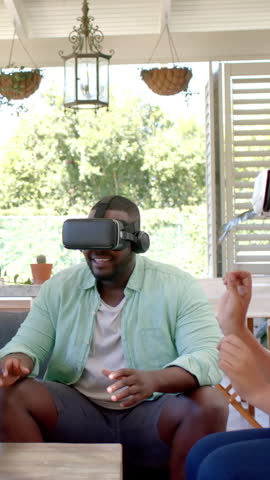 Interacting Diverse friends wearing VR headsets on patio with wicker planters, copy space. Outdoor, collaboration, contemporary, lifestyle, leisure, innovation, natural