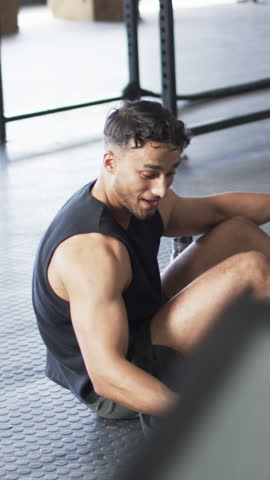 Vertical video: After finishing set man resting at gym rack explaining form to partner approaching. Strength, fitness, teamwork, motivation, workout, training, vertical video