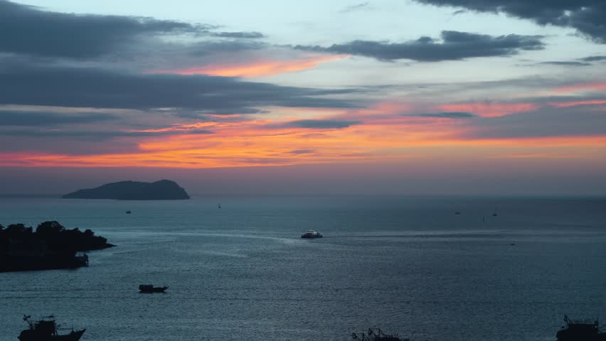 Beautiful aerial view of silhouetted islands and boats on the ocean water during a dramatic and colorful sunset in Kota Kinabalu Sabah