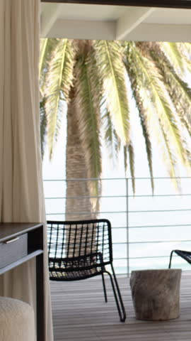 Vertical video: Romantic couple pulling suitcases onto deck upon arrival, embracing ocean view. Romance, travel, leisure, relaxation, sunset, coastal, vertical video