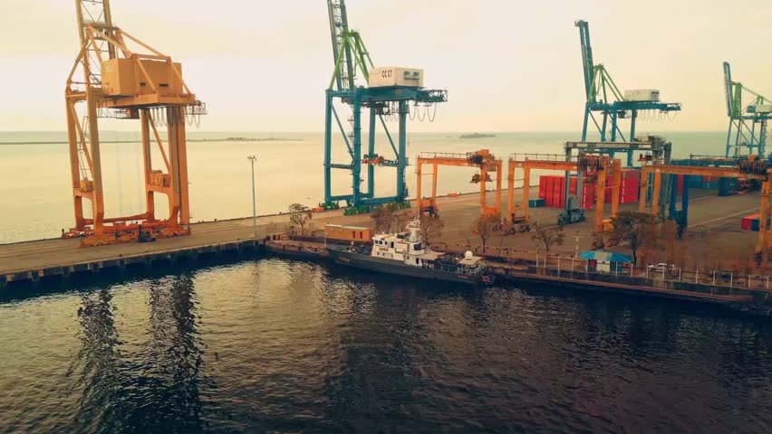 Aerial view of a large industrial port with towering cranes loading and unloading at the dockyard.