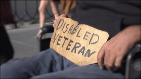 Disabled veteran in a wheelchair holding a sign, highlighting veteran support, accessibility, and social awareness in 4K. - Powered by Shutterstock - Get 15% off with code: PIKWIZARD15