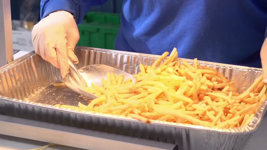 Close-up of scooping French fries into a bag, capturing food service, fast food preparation, and fresh fries in 4K detail.