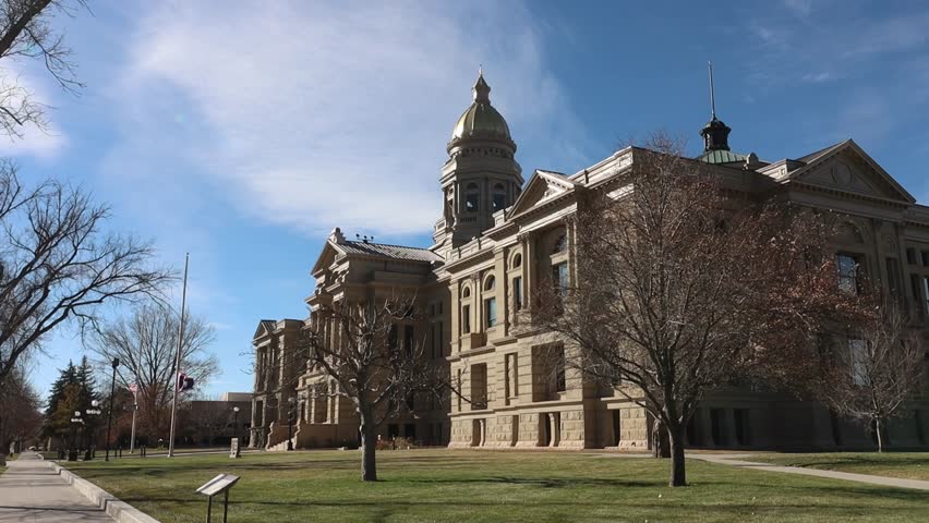 Wyoming State Capital building flags flying half mast in heavy wind.