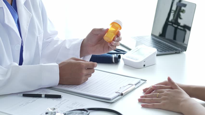 Doctor Holding Medicine Bottle Explaining Dosage to Patient