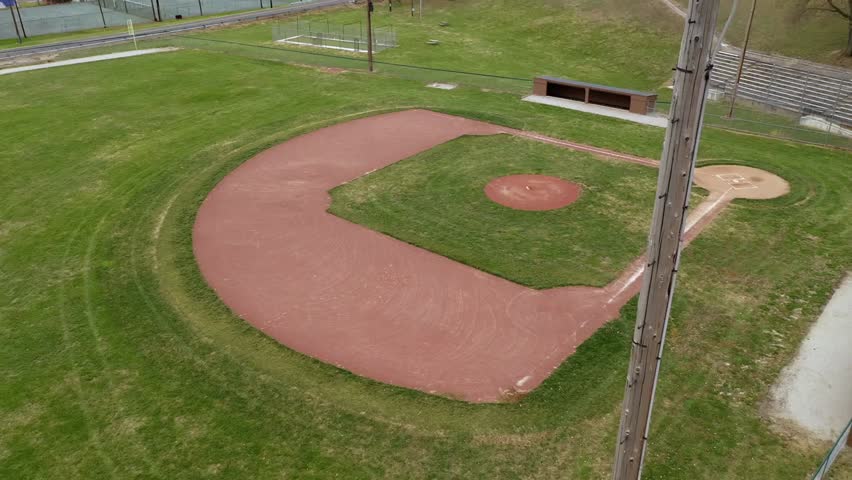 Aerial establishing shot of a baseball field from behind stadium lights, capturing sports venue, nighttime atmosphere, and field layout in 4K.