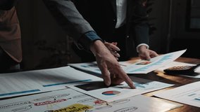 Business colleagues analyzing financial statistics and discussing a project in a dark office meeting room - Powered by Shutterstock - Get 15% off with code: PIKWIZARD15