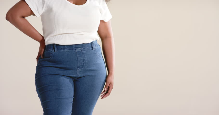 Camera zooming out showing African American woman modeling jeans and ribbed T-shirt in studio. Fashion, portrait, elegance, confidence, beauty, casual, style