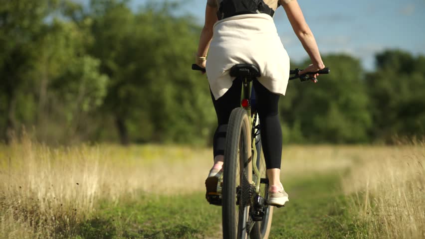 Woman Riding Bicycle On Paved Rural Road, Female Cyclist Outdoor Fitness Activity. Healthy Lifestyle And Sport, Bike Commuting And Recreation. Modern Mountain Bike Cycling In Nature, Fitness Training