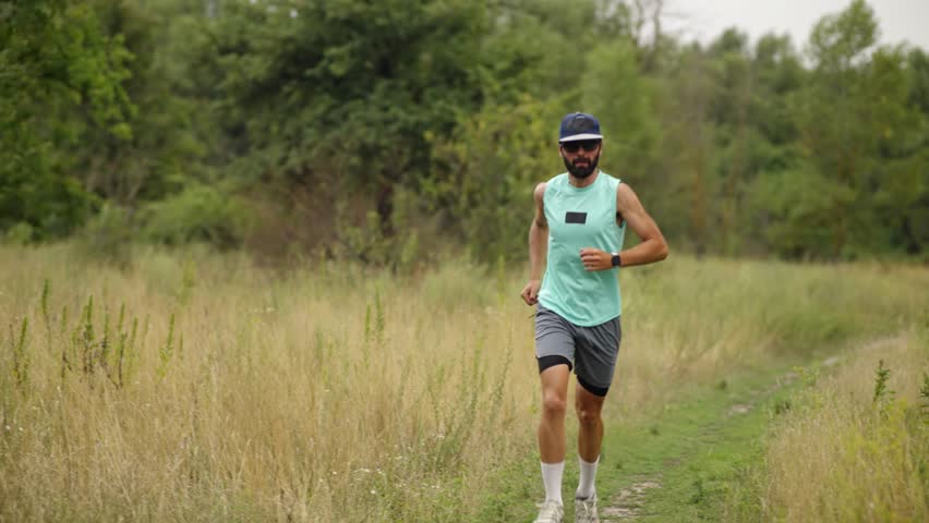 Male Runner Jogging On Rural Dirt Path. Athlete Training In Summer Field, Fitness Exercise Outdoors, Healthy Lifestyle Activity Runner. Sporty Man Running, Endurance Training, Trail Running Adventure