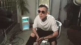 Trendy hip-hop and rap performer singing to professional camera, portrait. Recording musical video in modern studio, self-confidence musician making content for social media, tattoos on face and body - Powered by Shutterstock - Get 15% off with code: PIKWIZARD15