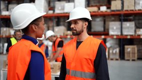 Diverse logistics center supervisor and worker shaking hands after discussing stock inventory and merchandise delivery, both wearing protective hard hats and high visibility vests - Powered by Shutterstock - Get 15% off with code: PIKWIZARD15