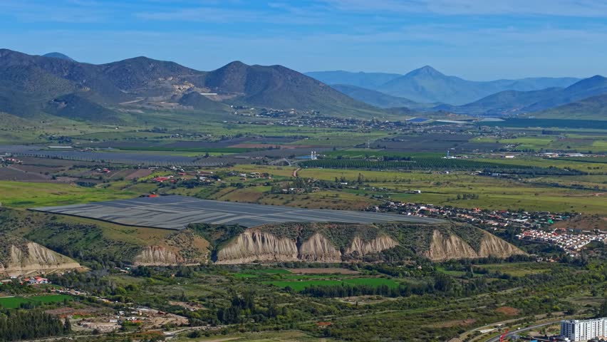 Aerial telephoto view of plantations with protective nets in the Limarí Valley with green mountains on a sunny day. Plantations for Chilean pisco.