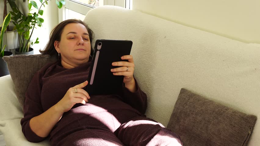 Woman is lying at the couch and read e-book - Powered by Shutterstock - Get 15% off with code: PIKWIZARD15