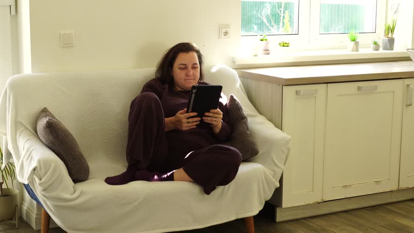 Woman is lying at the couch and read e-book - Powered by Shutterstock - Get 15% off with code: PIKWIZARD15