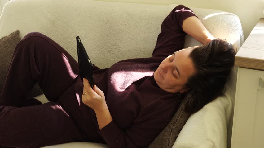 Woman is lying at the couch and read e-book - Powered by Shutterstock - Get 15% off with code: PIKWIZARD15