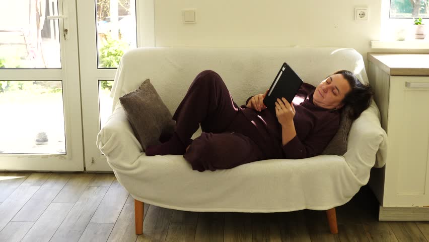 Woman is lying at the couch and read e-book - Powered by Shutterstock - Get 15% off with code: PIKWIZARD15