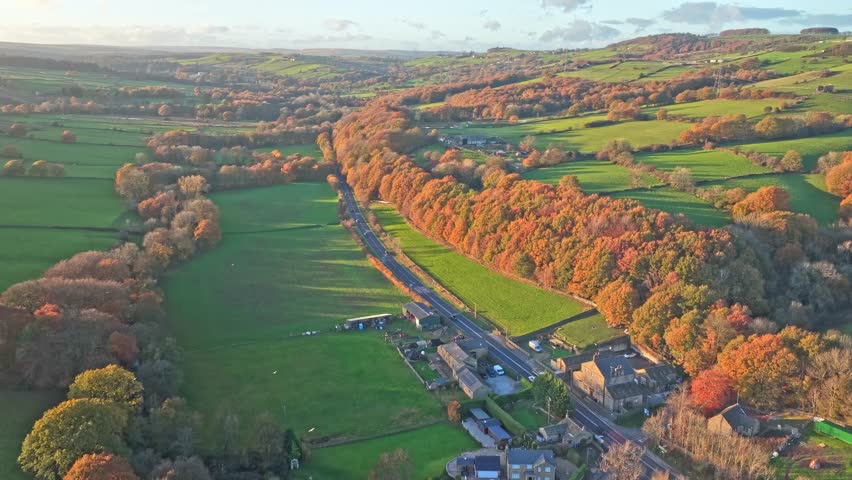 Drone gradually retreats from Underbank Activity Centre, revealing panoramic views of the reservoir, facility infrastructure and surrounding moorland valley landscape layered beneath autumnal woodland