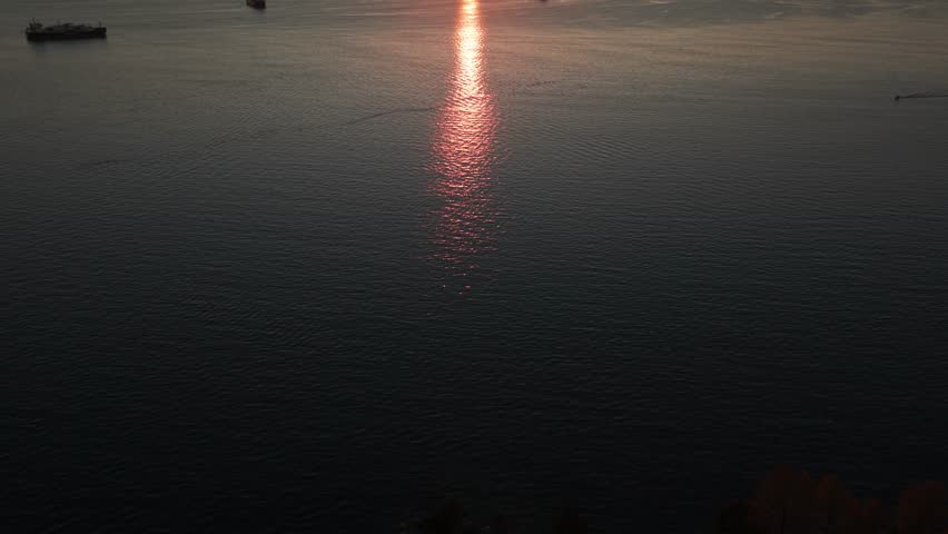 Wide tilting up aerial shot of Burrard Inlet at sunset during a clear evening in Vancouver, British Columbia, Canada. 4K