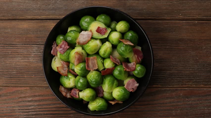 Brussels sprouts with pancetta top view in black bowl wood