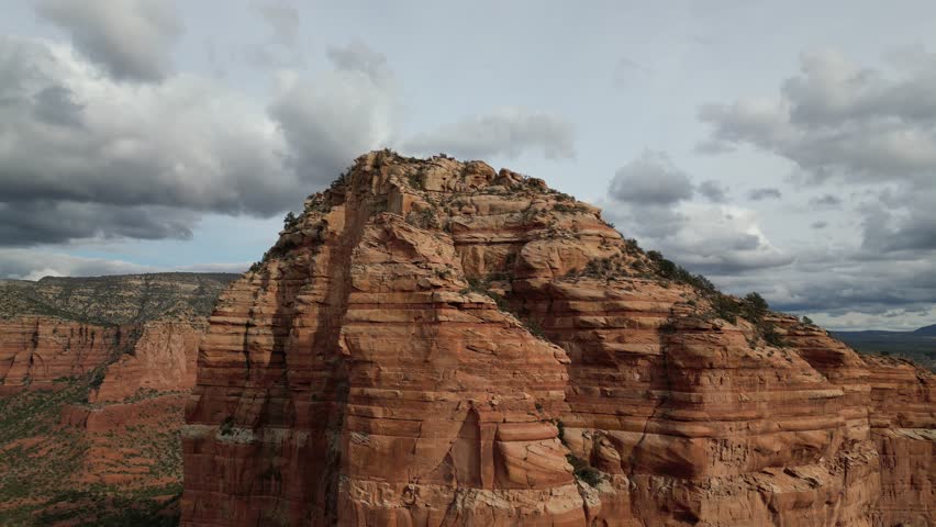 Aerial drone footage of Courthouse Butte in Sedona, Arizona, highlighting towering red sandstone formation surrounded by desert landscape, cliffs, and scenic southwestern terrain under clear skies.