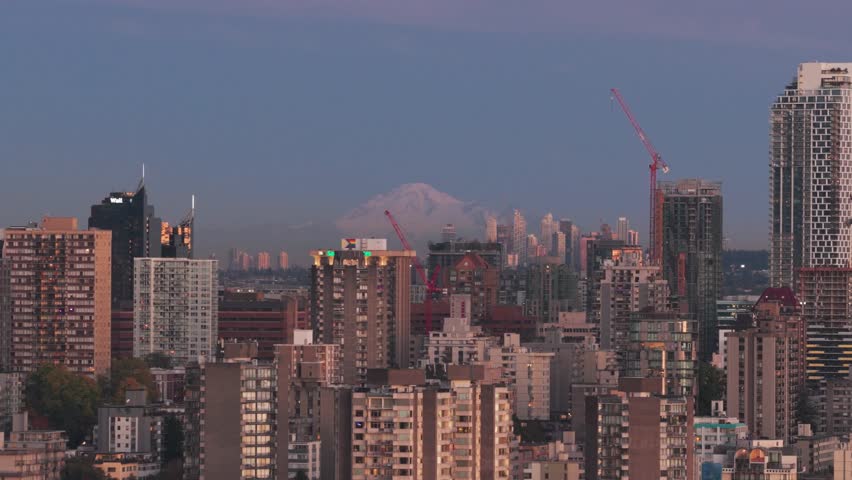 Telephoto aerial panning shot of the downtown skyline at low light in Vancouver, British Columbia, Canada. 4K