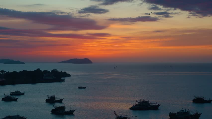 Stunning aerial view of fishing boats silhouetted in Kota Kinabalu harbor against vibrant orange and blue sunset sky in Sabah Malaysia