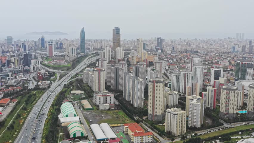 Aerial view of a dense cityscape featuring skyscrapers, highways bustling with cars, and buildings under a cloudy sky, Istanbul, Istanbul, Turkiye.