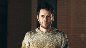 A young man with dark hair in a sweater smiles and waves at the camera, showing friendliness, casual interaction, and approachable indoor demeanor. - Powered by Shutterstock - Get 15% off with code: PIKWIZARD15