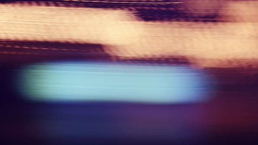 Slow shutter speed footage with motion blur and smeared colorful bokeh circles from street lights at night, abstract dreamy background. 4K, selective focus.