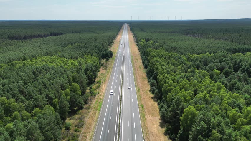 Highway, green energy, wind turbines on the horizon produce energy in the forest near the road, highway view, power extraction, alternative energy sources, wind force.