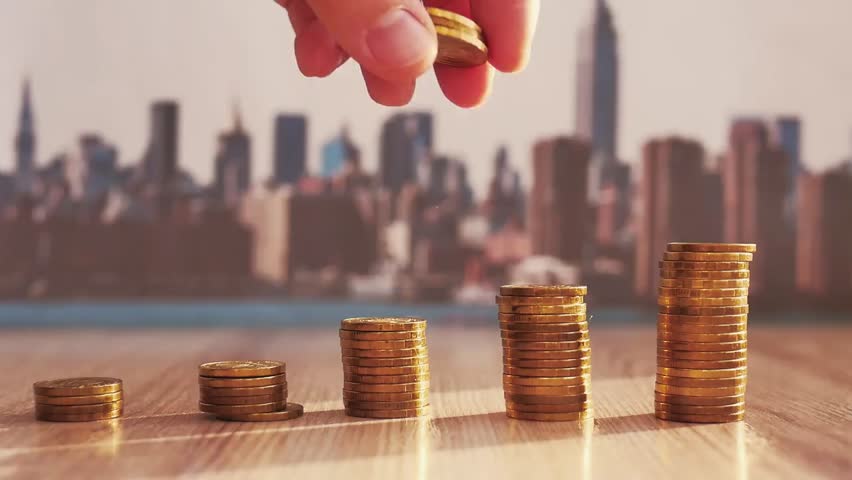 Hand placing a dollar coin on a stacked coin graph, symbolizing financial growth, saving, investment, and business success concept.