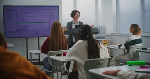 Woman Computer Science Teacher Demonstrates Programming Logic On Big Screen During Classroom Lesson. Concept Coding Education, Digital Literacy, Technology Integration, And Modern Teaching Approach. - Powered by Shutterstock - Get 15% off with code: PIKWIZARD15