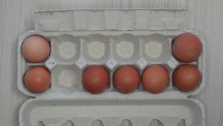 Woman hand taking egg from box, top view food video. Top view video of a female hand taking an egg from a box on a kitchen table. Concept of cooking preparation, fresh organic food, breakfast
