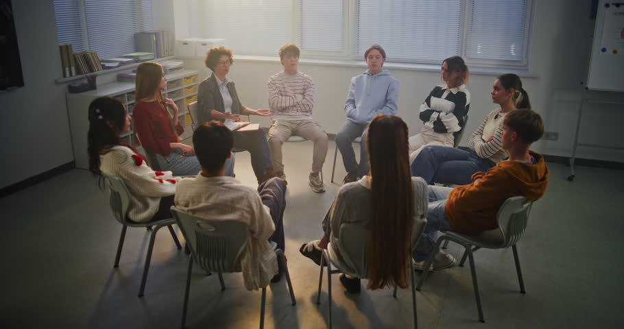 Teacher Facilitates Mental Health Discussion With Teenagers in Bright Classroom, Promoting Empathy and Trust. Concept Emotional Growth, Student Support, and Modern School Environment. Dolly Shot.