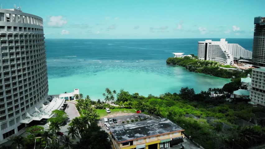 Aerial drone footage of Guam’s pristine beach with turquoise waters, palm trees, and coral reefs. Stunning tropical island view perfect for travel, tourism, and coastal nature visuals.