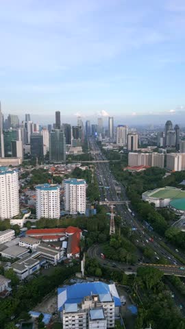 Aerial view of city traffic and modern skyline in Jakarta, Indonesia. Busy urban highway, tall skyscrapers, and green spaces in Southeast Asia